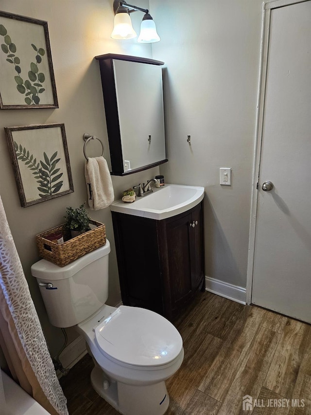 bathroom with baseboards, wood finished floors, toilet, and vanity