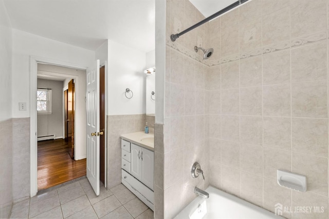 bathroom with baseboard heating, tile walls, tile patterned flooring, shower / washtub combination, and vanity