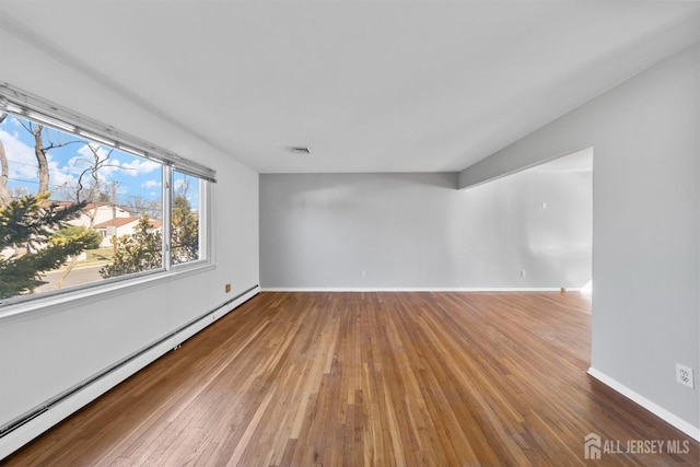 spare room with a baseboard radiator, wood-type flooring, and baseboards