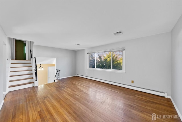 unfurnished living room featuring a baseboard heating unit, hardwood / wood-style flooring, baseboards, and stairs