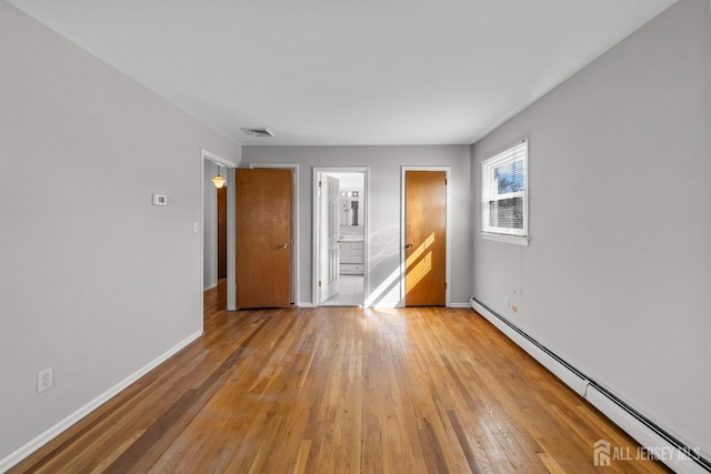 unfurnished room featuring a baseboard radiator, light wood-style floors, and baseboards