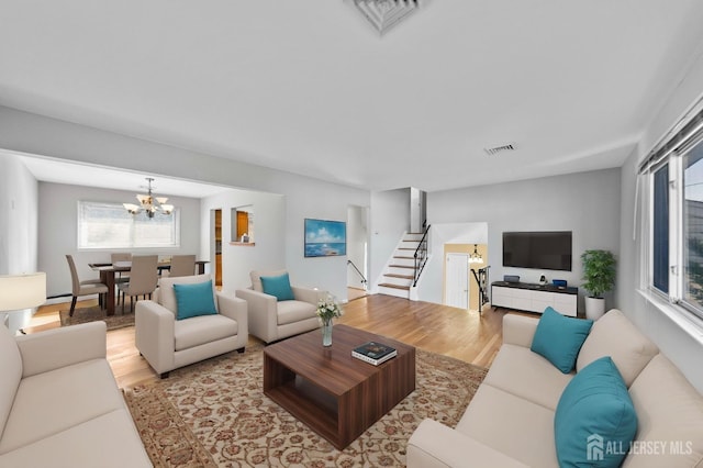 living room with plenty of natural light, wood finished floors, a chandelier, and stairs