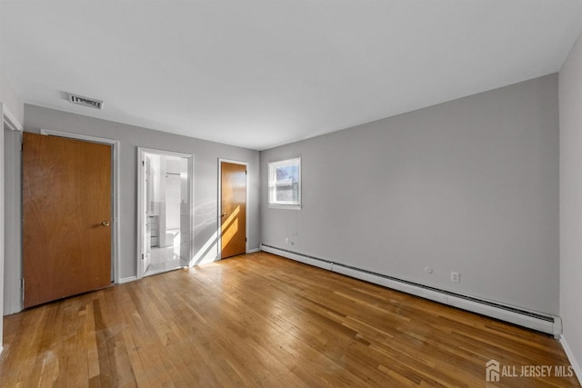 empty room with baseboard heating, wood-type flooring, and baseboards