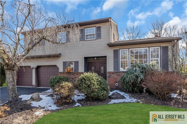 view of front of house with a garage, brick siding, driveway, and a front lawn