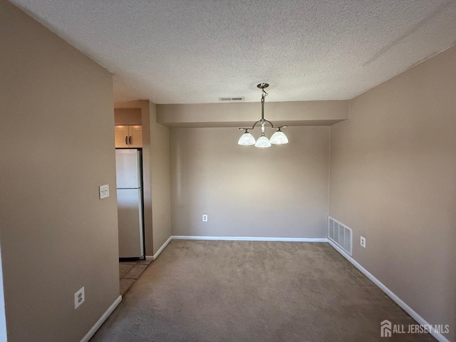 empty room featuring a chandelier, visible vents, and baseboards