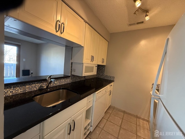 kitchen with white appliances, visible vents, decorative backsplash, white cabinetry, and a sink