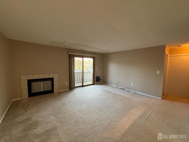 unfurnished living room with baseboards, light colored carpet, a textured ceiling, and a tiled fireplace