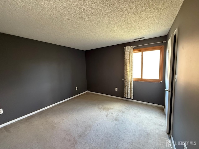 carpeted empty room featuring a textured ceiling, visible vents, and baseboards