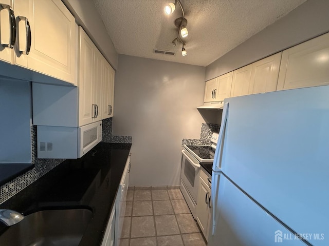 kitchen with dark countertops, decorative backsplash, white cabinetry, white appliances, and under cabinet range hood