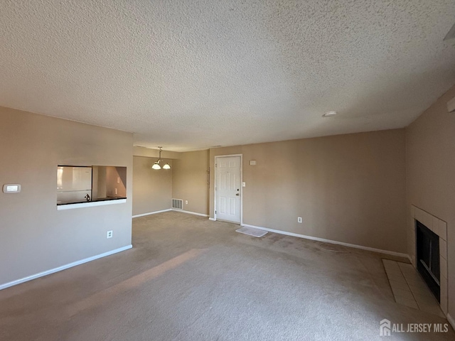 unfurnished living room featuring baseboards, a textured ceiling, visible vents, and a tiled fireplace