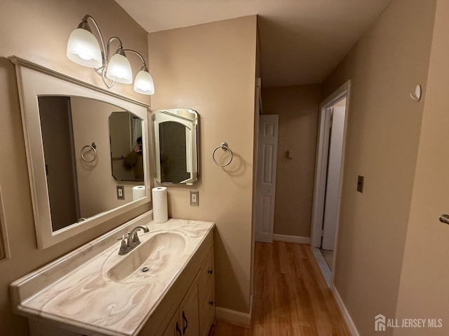 bathroom with baseboards, wood finished floors, and vanity