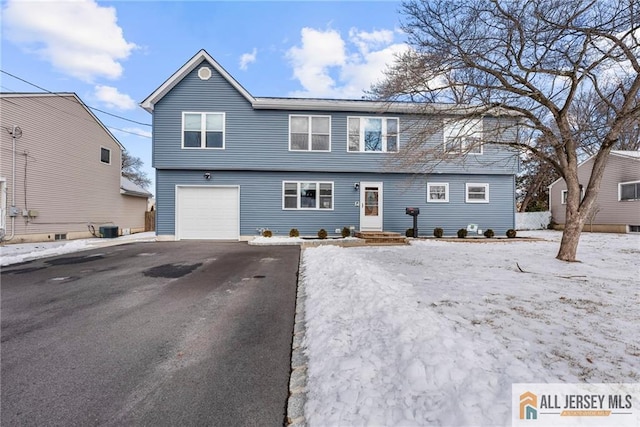 colonial-style house with a garage, aphalt driveway, and central air condition unit