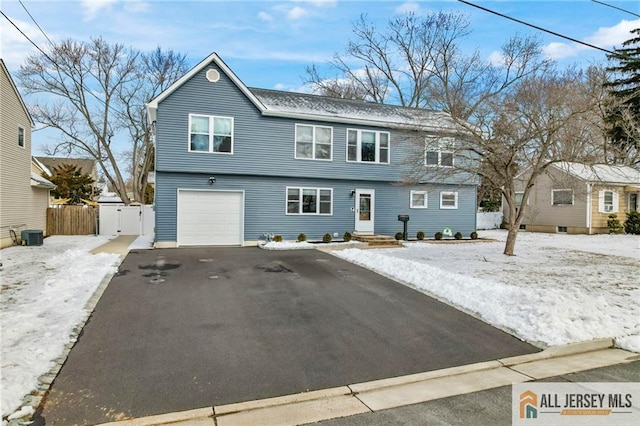 colonial-style house featuring aphalt driveway, fence, and an attached garage