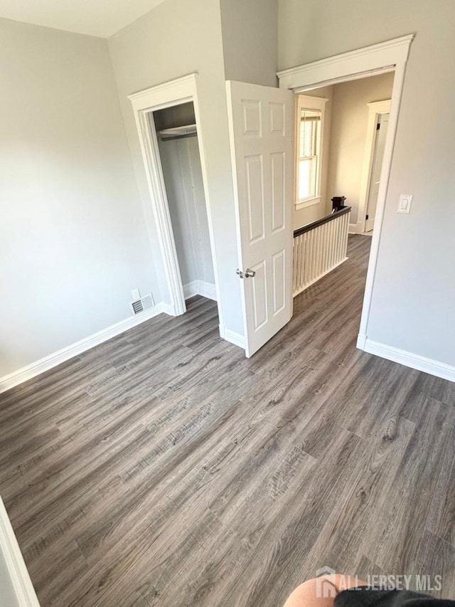 unfurnished bedroom with dark hardwood / wood-style flooring and a closet