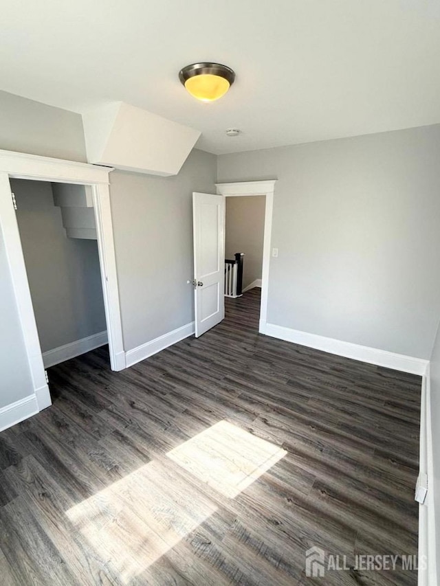 unfurnished bedroom with dark hardwood / wood-style flooring and a closet