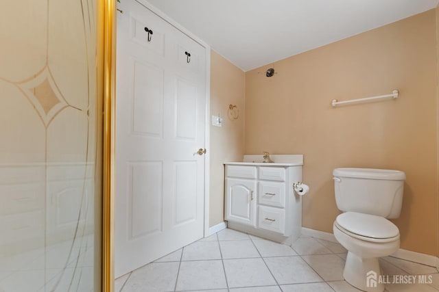 bathroom featuring vanity, baseboards, toilet, tile patterned floors, and walk in shower