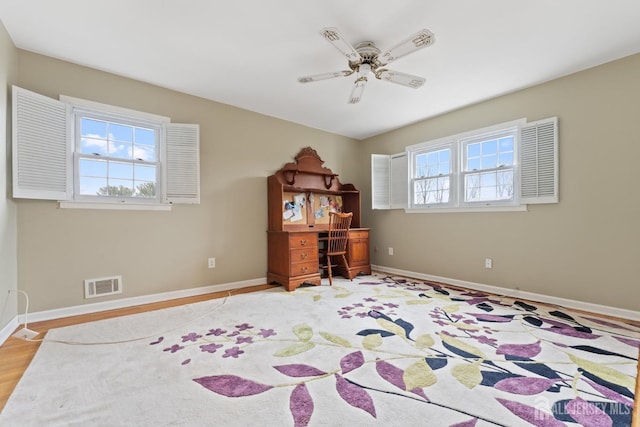 office space featuring baseboards, ceiling fan, visible vents, and wood finished floors