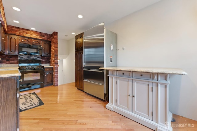 kitchen featuring tasteful backsplash, dark brown cabinets, black appliances, and light wood finished floors