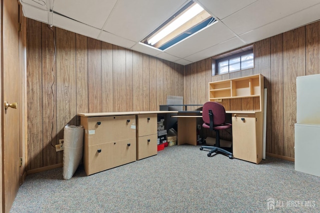 office area with light colored carpet, a drop ceiling, and wooden walls