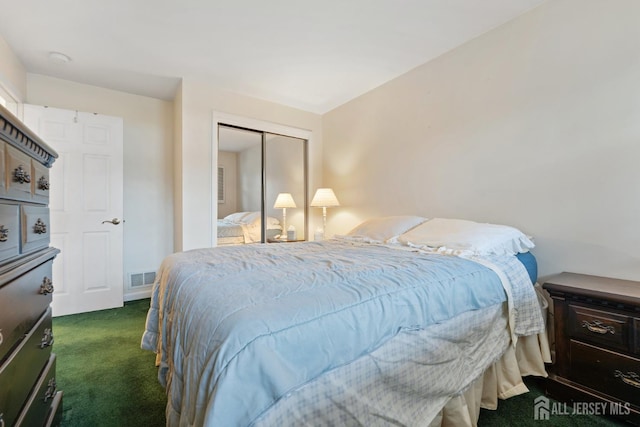 bedroom with dark colored carpet, visible vents, and a closet