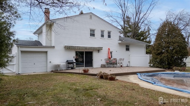 back of property featuring a covered pool, a wooden deck, a lawn, and a chimney