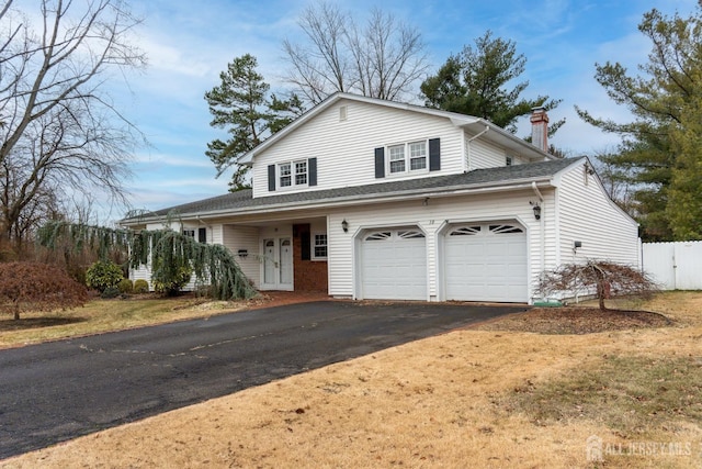 view of front of house with an attached garage, driveway, and a chimney