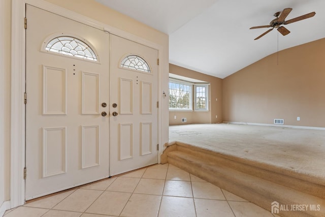 entrance foyer with light tile patterned floors, visible vents, ceiling fan, vaulted ceiling, and light carpet