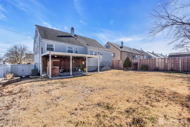 rear view of house with a fenced backyard, a chimney, a patio area, and central AC