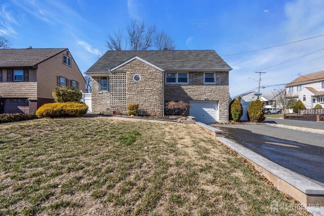 traditional-style home with a shingled roof, an attached garage, a front lawn, stone siding, and driveway