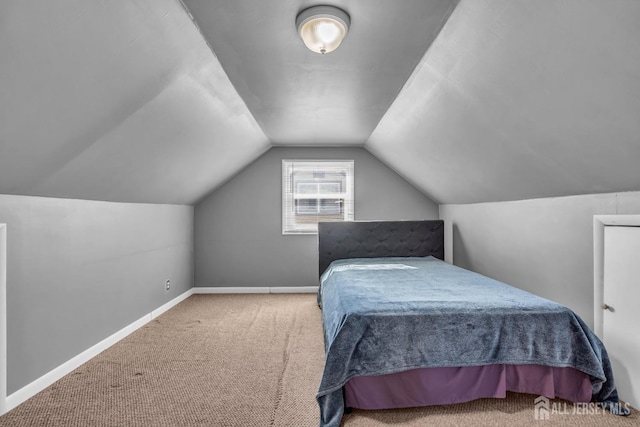bedroom featuring baseboards, lofted ceiling, and carpet