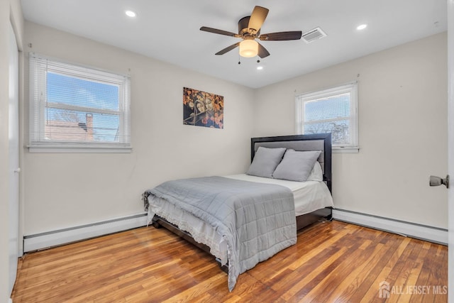 bedroom with recessed lighting, visible vents, wood finished floors, and a baseboard radiator