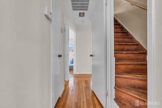 hallway featuring baseboards, visible vents, stairway, and light wood-style floors