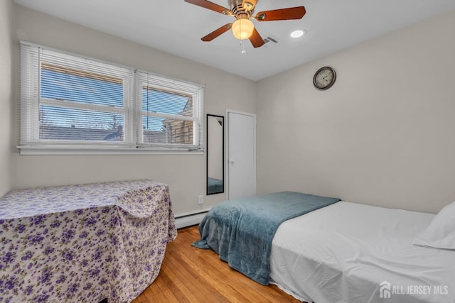bedroom featuring ceiling fan, visible vents, baseboard heating, light wood-style floors, and recessed lighting