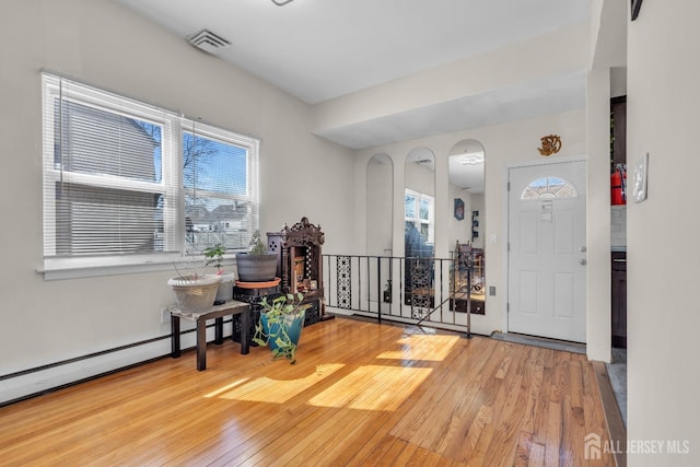 foyer entrance with visible vents, wood-type flooring, and a healthy amount of sunlight