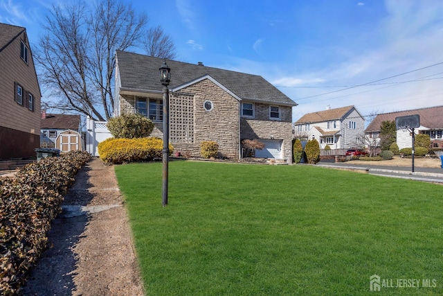 view of front facade with a front lawn, stone siding, a garage, a storage shed, and an outdoor structure