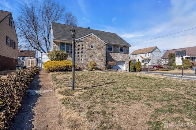 bungalow-style home with stone siding, a storage shed, a garage, a front yard, and an outbuilding