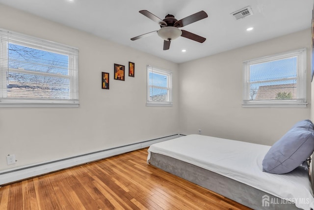 bedroom with baseboard heating, recessed lighting, a ceiling fan, wood finished floors, and visible vents