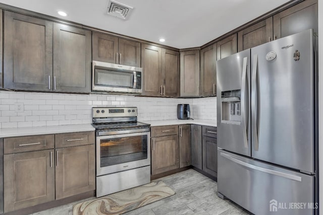 kitchen featuring light countertops, tasteful backsplash, dark brown cabinetry, and stainless steel appliances