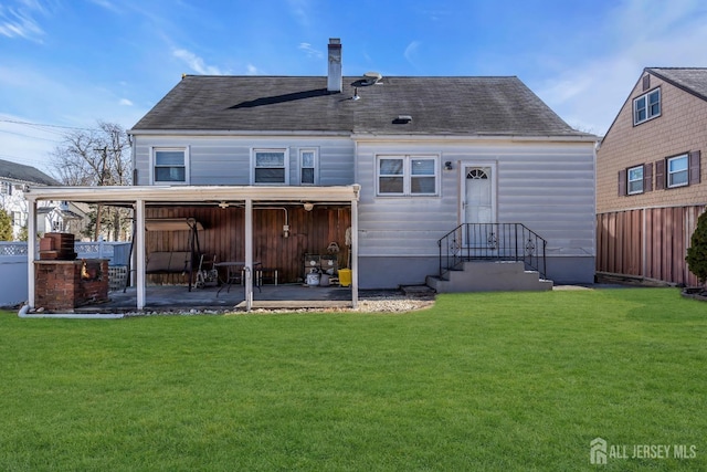 back of property with a patio, a shingled roof, fence, and a yard