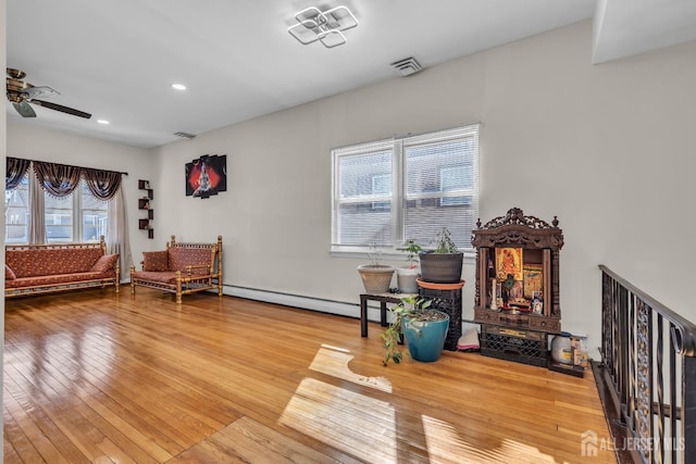 sitting room with a ceiling fan, visible vents, a baseboard heating unit, recessed lighting, and hardwood / wood-style floors