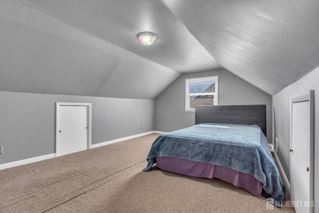 carpeted bedroom with baseboards and vaulted ceiling