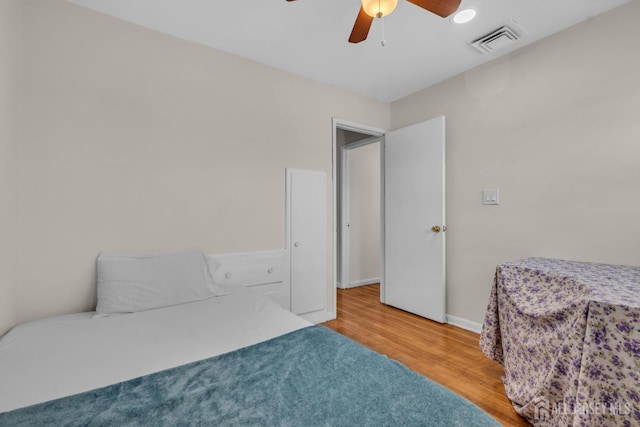 bedroom featuring baseboards, a ceiling fan, wood finished floors, and visible vents