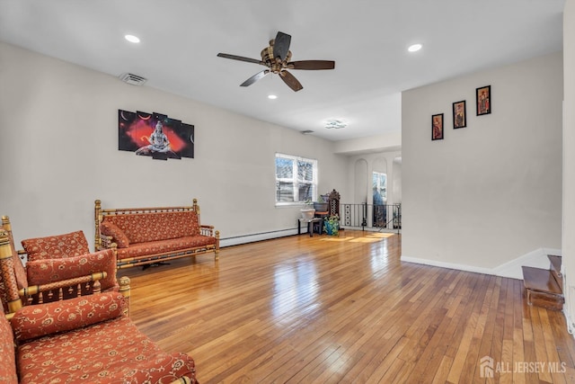 living area featuring visible vents, baseboard heating, recessed lighting, hardwood / wood-style flooring, and a ceiling fan