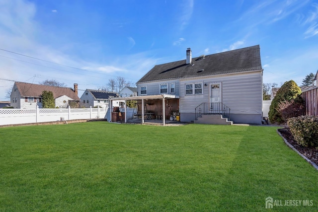 rear view of house with a lawn, a fenced backyard, a chimney, and a shingled roof