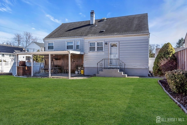 rear view of house featuring a lawn, fence, a shingled roof, and a patio area