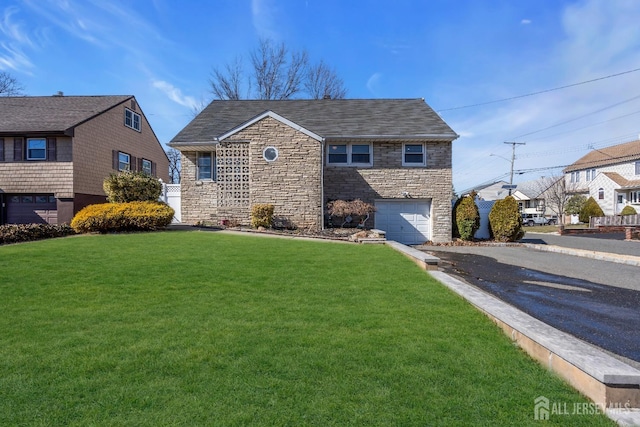 traditional-style home with an attached garage, a front lawn, stone siding, and aphalt driveway