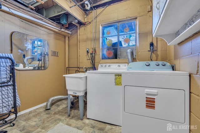 washroom featuring a sink, baseboards, laundry area, and washing machine and dryer