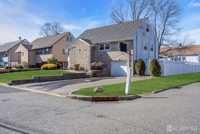 traditional-style home with fence, a residential view, stone siding, a garage, and driveway