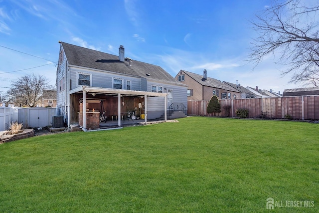 back of property with a yard, a chimney, a fenced backyard, and a patio area