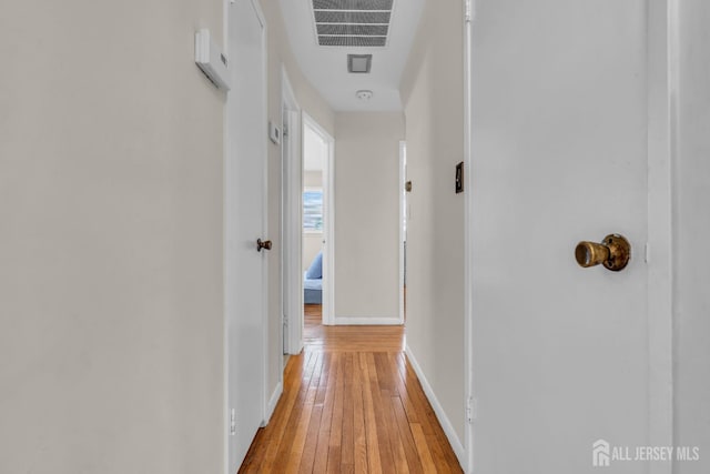 hall with baseboards, visible vents, and light wood-style floors